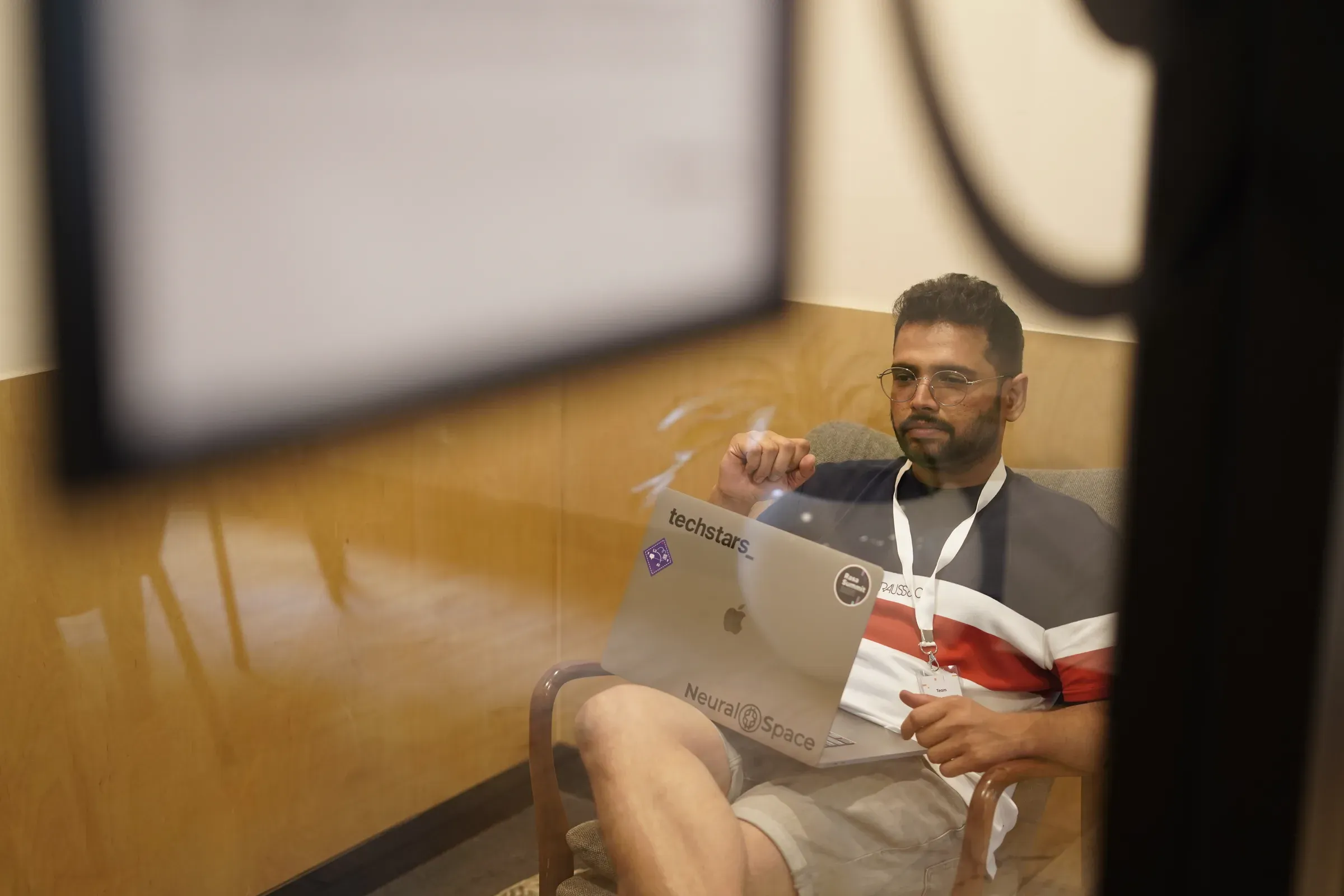 Ayushman Dash working on a laptop covered in Techstars and NeuralSpace stickers