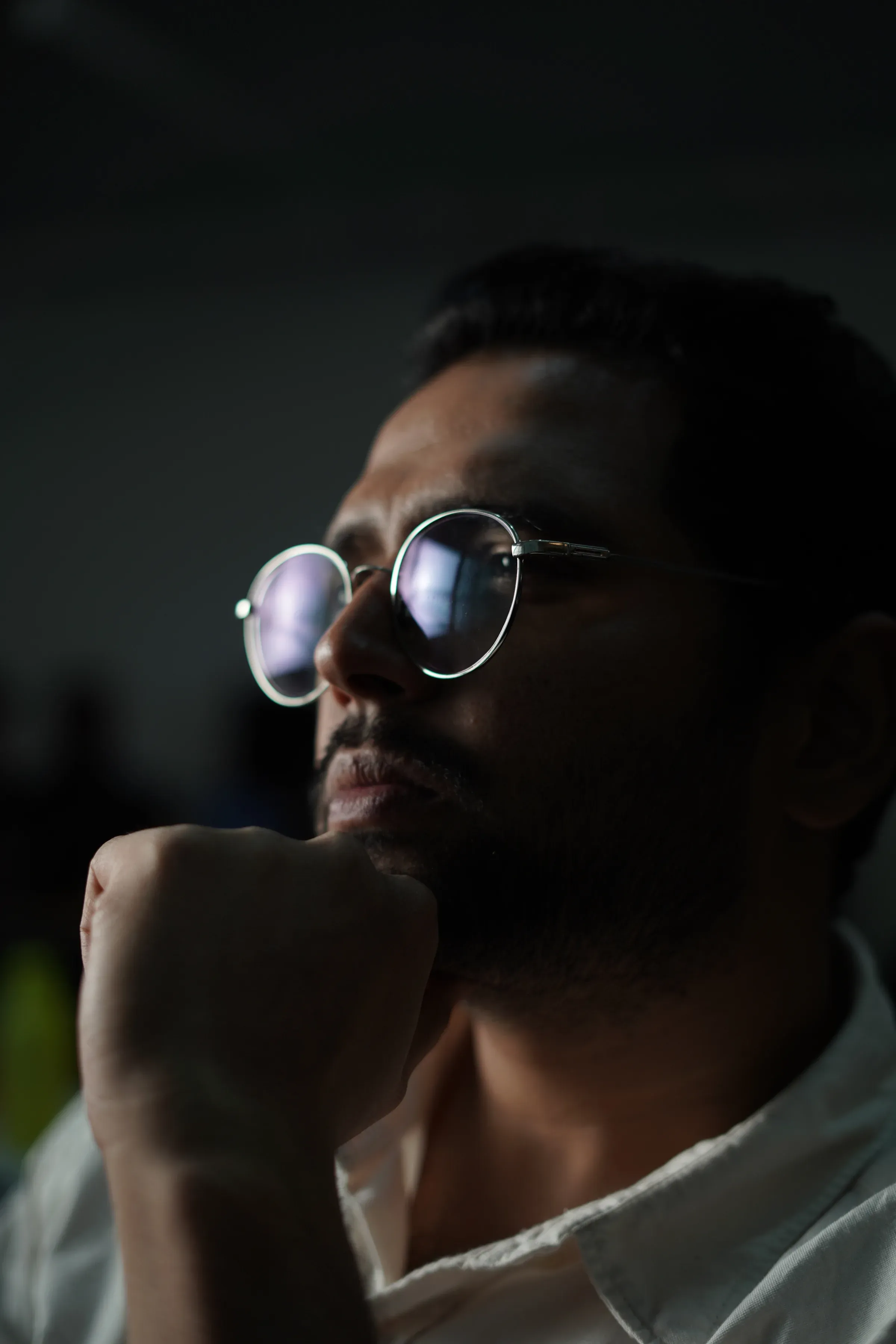 Portrait of Ayushman Dash at a desk in low light, pen in hand