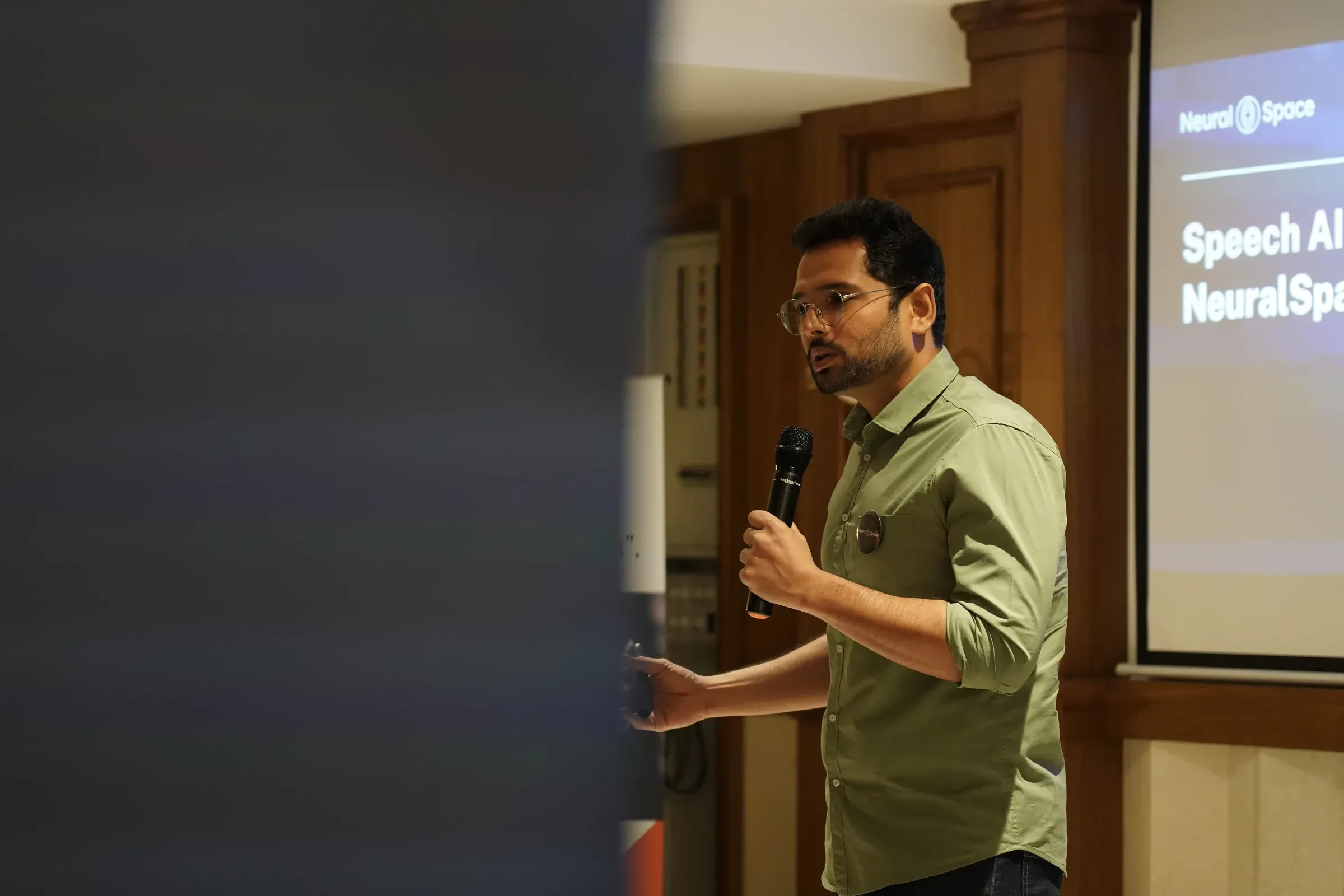 Ayushman Dash giving a talk on speech AI, a NeuralSpace slide behind him