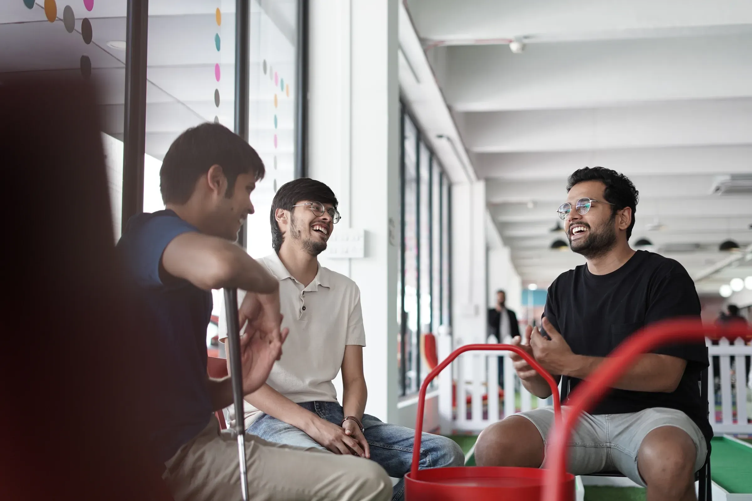 Ayushman Dash laughing with two colleagues in an open-plan office