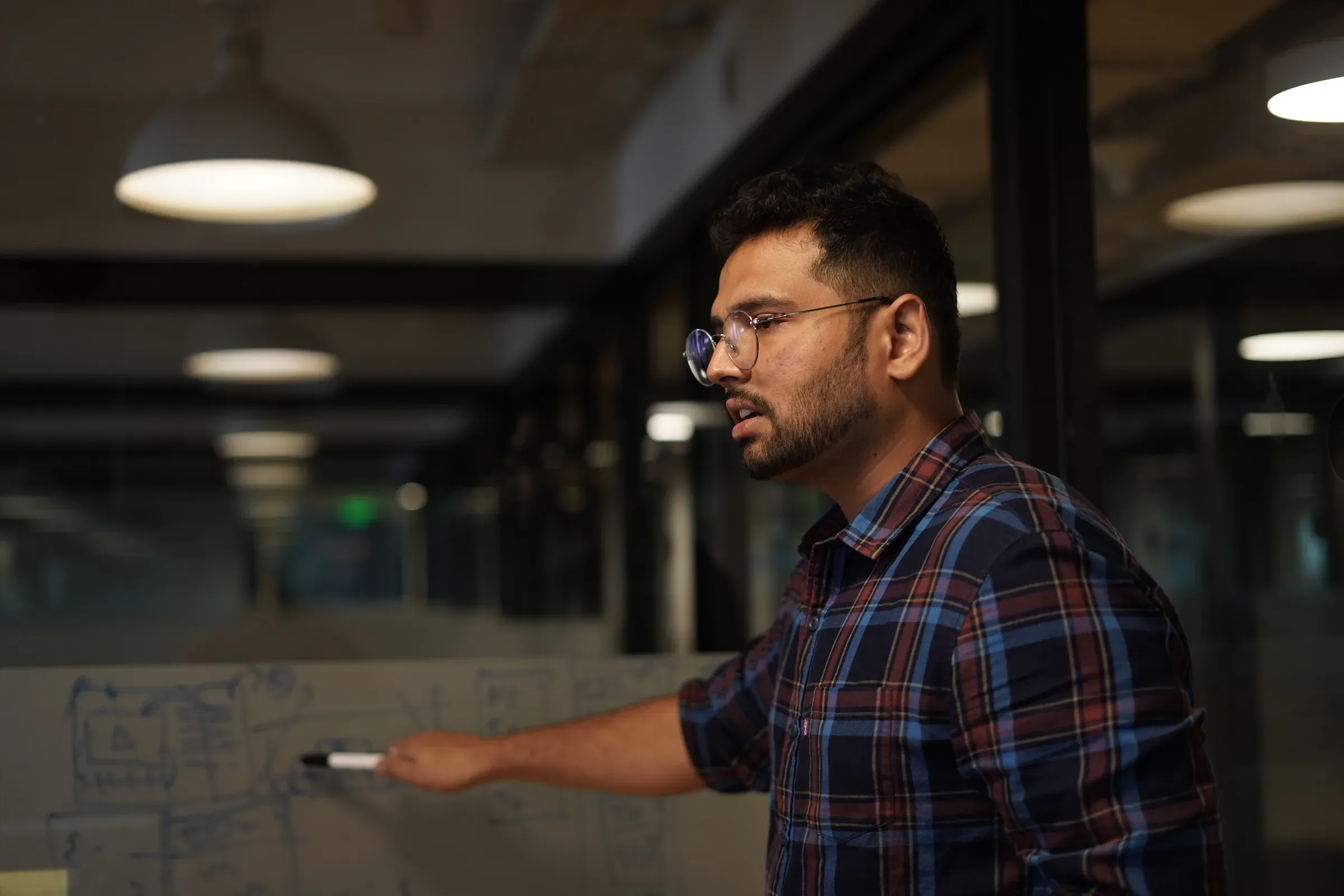 Ayushman Dash drawing a system architecture on a glass whiteboard